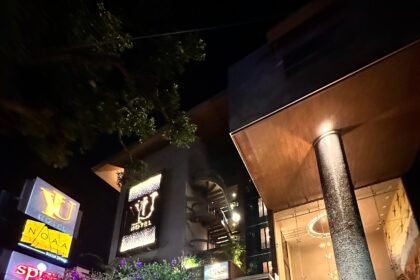 Yu Hotels lit up against a dark sky with a quiet road in front